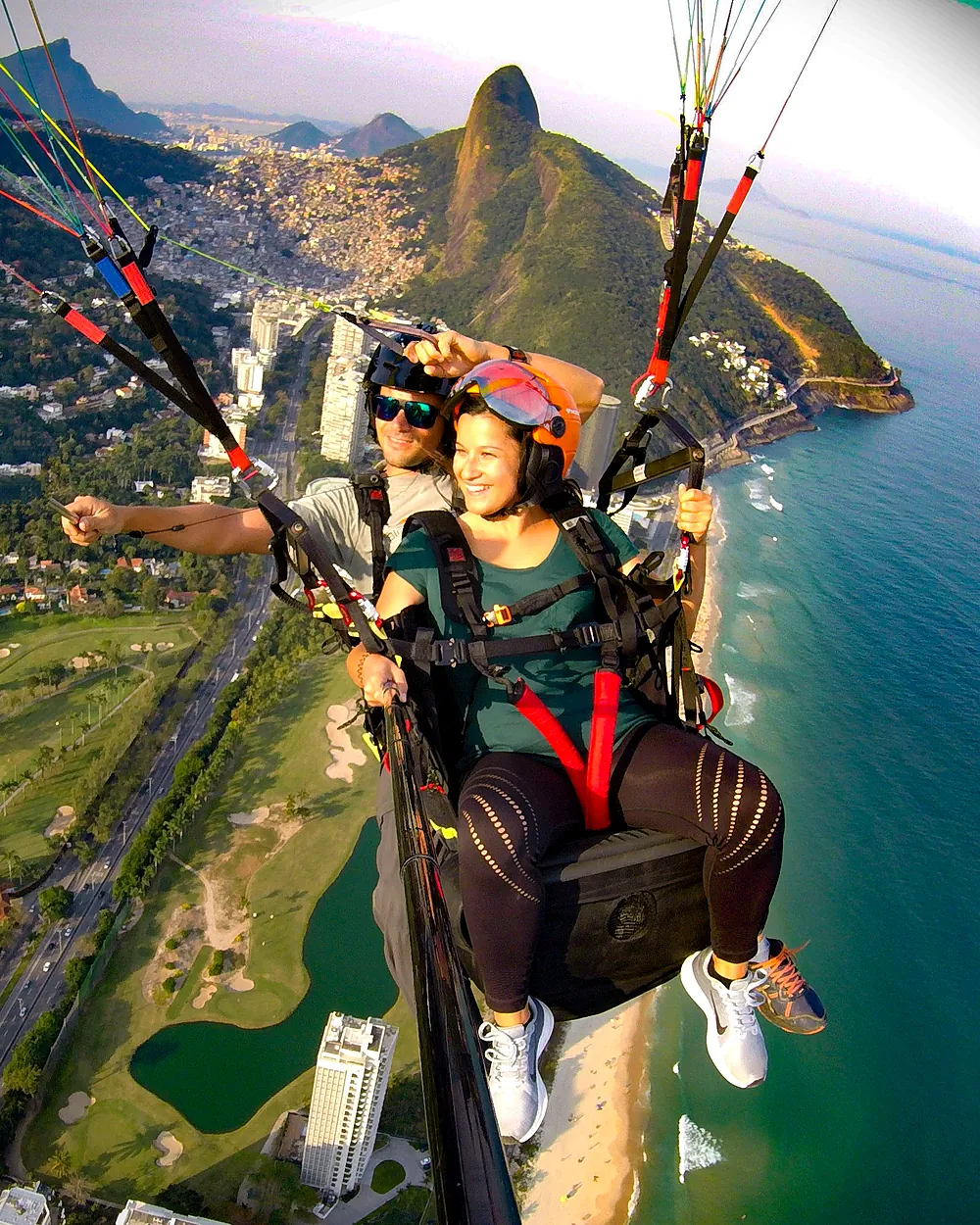 Passageira em voo de parapente com o Morro Dois Irmãos e a Praia de São Conrado ao fundo